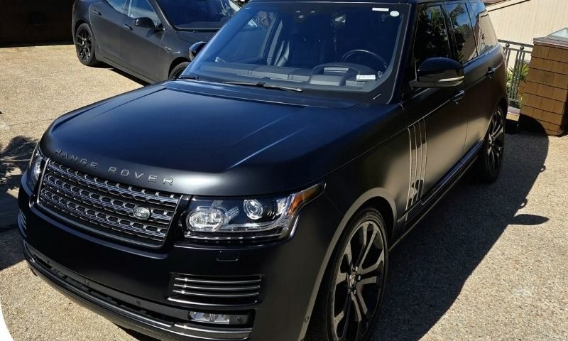professional car detailer inspecting vehicle paint condition before detailing